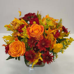Orange and red flower arrangement in a clear glass vase