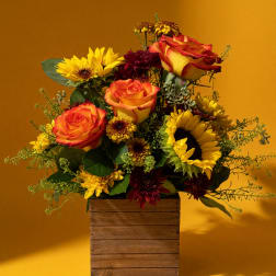 Bouquet of orange roses and yellow sunflowers in a wooden box