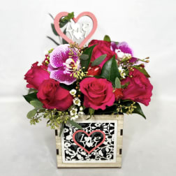 Pink rose arrangement in a decorative wooden box with a heart topper