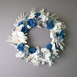 Blue and white floral wreath with dried accents on a gray wall