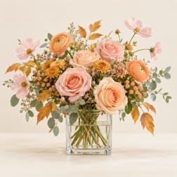 Peach and pink roses with pale cosmos in a clear glass vase