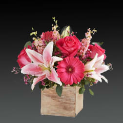 Pink roses and lilies arranged in a wooden box