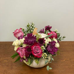 Pink and purple roses with white flowers in a white pumpkin vase