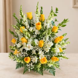 Yellow roses and white flowers arranged in a low vase