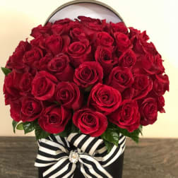 Red rose arrangement in a black box with a striped ribbon