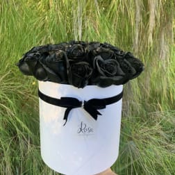 Black roses arranged in a white round box with a black ribbon