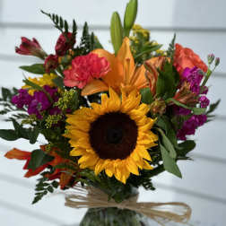 Mixed bouquet with a sunflower and orange lily in a glass vase