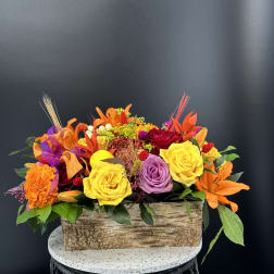 Bright mixed flower arrangement in a rustic rectangular wooden container