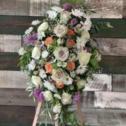 Standing floral spray with white roses, daisies, and purple accents