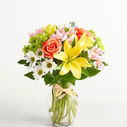 Mixed bouquet of lilies, roses, and daisies in a glass vase