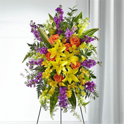 Tall floral standing spray with yellow lilies, orange roses, and purple flowers