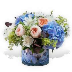 Blue and blush flowers arranged in a glass vase