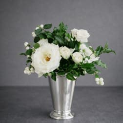 White roses and berries arranged in a silver vase