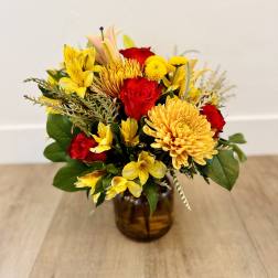 Bouquet of red roses and yellow flowers in an amber glass vase