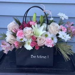 Pink and white flower arrangement in a black gift bag with "Be Mine!" text