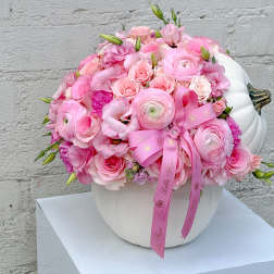 Pink floral arrangement in a white pumpkin-shaped vase with a ribbon bow