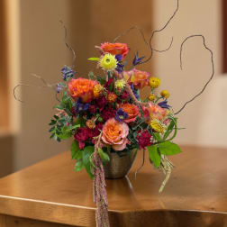 Colorful mixed flower arrangement in a small metal vase