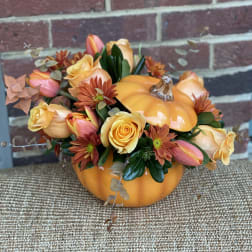 Pumpkin-shaped floral arrangement with yellow roses and orange daisies