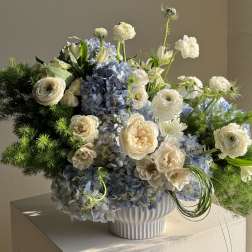 Blue hydrangea and white flower arrangement in a white vase