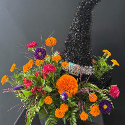 Bright orange, pink, and purple flowers arranged around a black tinsel tree centerpiece.