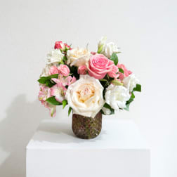 Pink and white rose bouquet in a textured glass vase