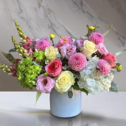 Mixed bouquet in a white vase with pink, cream, and white blooms