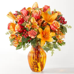 Orange and pink mixed bouquet in an amber glass vase