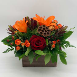 Orange lilies and red roses arranged in a wooden box
