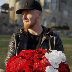 Large red floral arrangement in a black hatbox with white orchids and pearl strands