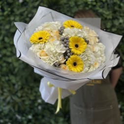 Bouquet of yellow gerbera daisies and white roses wrapped in white paper