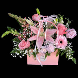 Pink floral arrangement in a pink box with ribbon