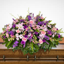 Large pink and purple floral spray on a wooden casket
