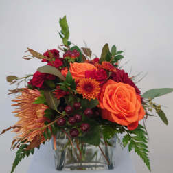 Orange and red mixed bouquet in a clear glass vase