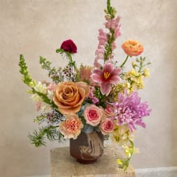Mixed bouquet in a brown vase with pink, peach, and yellow flowers