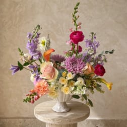 Colorful mixed flower arrangement in a white vase on a round pedestal table