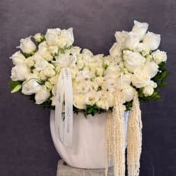 White rose arrangement in a white vase with trailing cream accents
