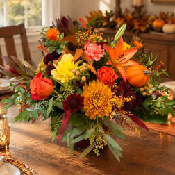 Autumn floral arrangement with orange lilies, roses, and chrysanthemums in a vase