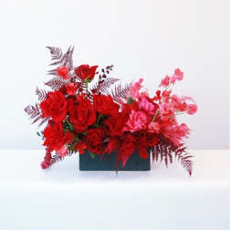 Red and pink rose arrangement in a rectangular black container