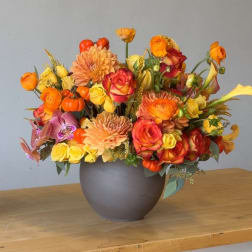 Orange and yellow floral arrangement in a gray vase