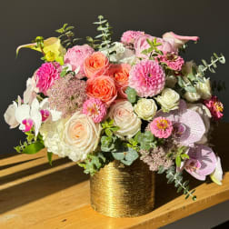 Mixed bouquet of pink, peach, and white flowers in a gold vase
