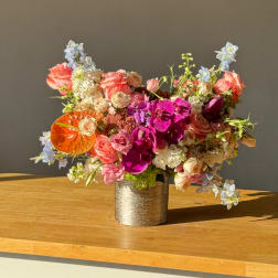 Mixed bouquet of pink, peach, and purple flowers in a metallic vase
