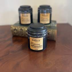 Black tea tin with gold label on a wood surface, with two similar tins blurred behind on stacked books.