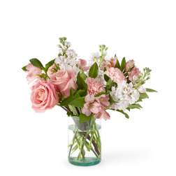 Pink roses, carnations, and white stock arranged in a clear glass cylinder vase