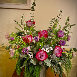 Garden-style arrangement of pink roses and purple anemones in a tall metal vase