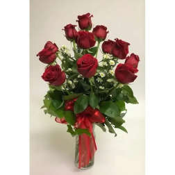 Red roses arranged in a clear glass vase with a red ribbon