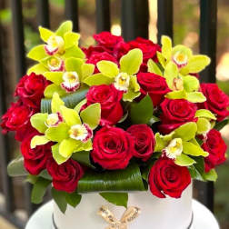 Red roses and lime orchids arranged in a white hat box