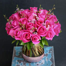 Pink roses arranged in a glass vase with small filler flowers