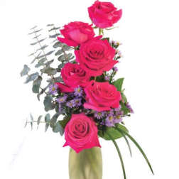 Pink roses arranged in a tall vase with purple filler flowers