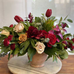 Mixed red and cream roses in a low terracotta vase
