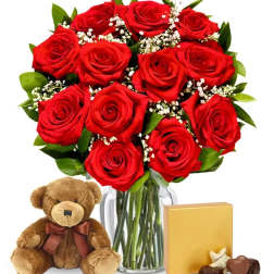 Bouquet of red roses in a glass vase with a teddy bear and chocolates
